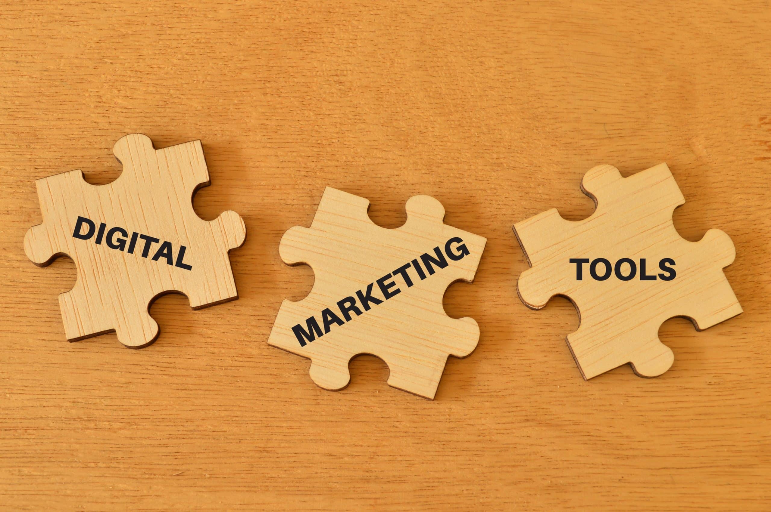 Three puzzle pieces on a wooden surface with the words "Digital Marketing" printed on them.